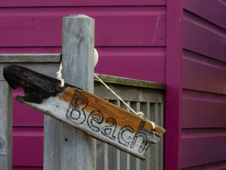 a wooden sign hanging from the side of a wooden pole