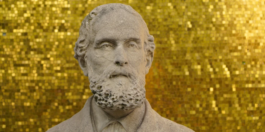 a bust of a man standing next to a golden wall