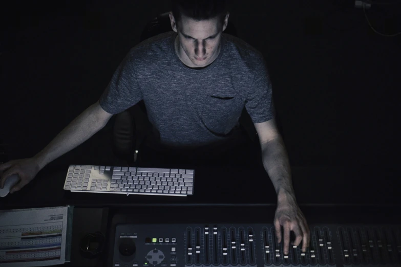 a man works in the dark on a computer with headphones