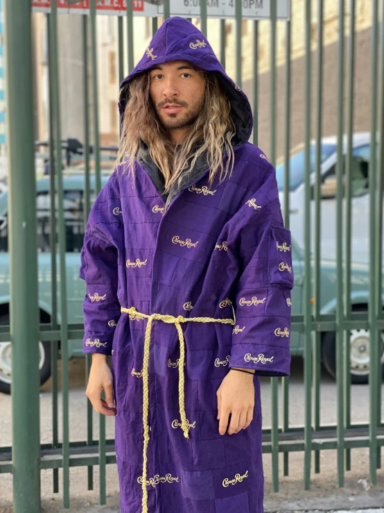 a man is wearing a purple robe and standing next to some fences