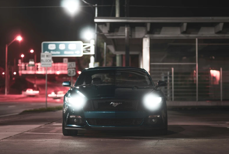 a car in front of a street sign at night