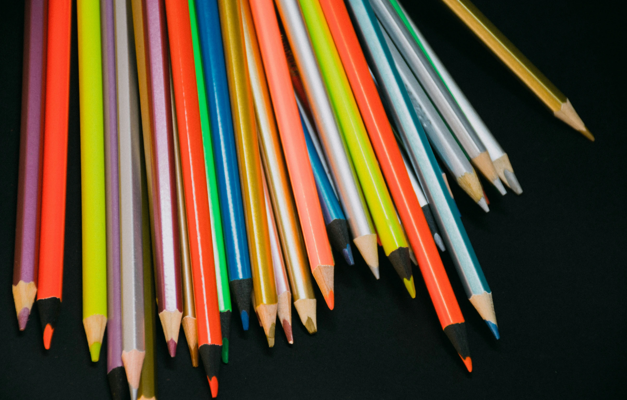 multicolored pencils lined up with one orange and yellow