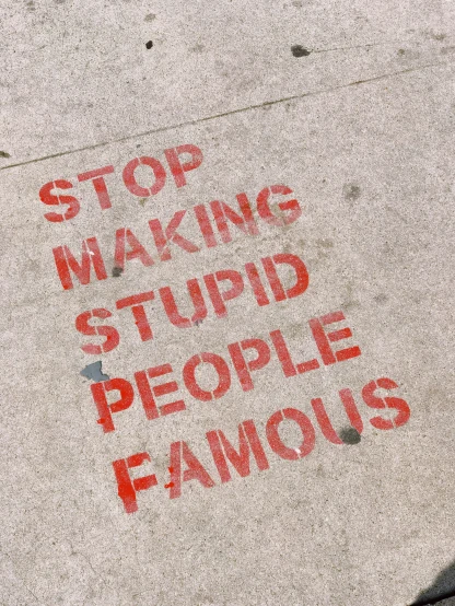 a red and white sidewalk with stop making stupid people famous