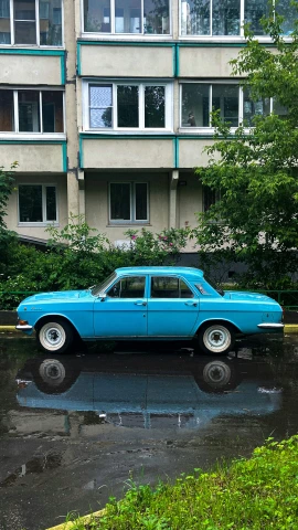 an old car parked in front of a building in the rain