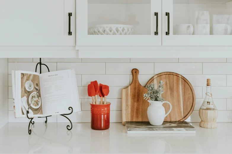 an open book on a kitchen counter with a  board and knifes