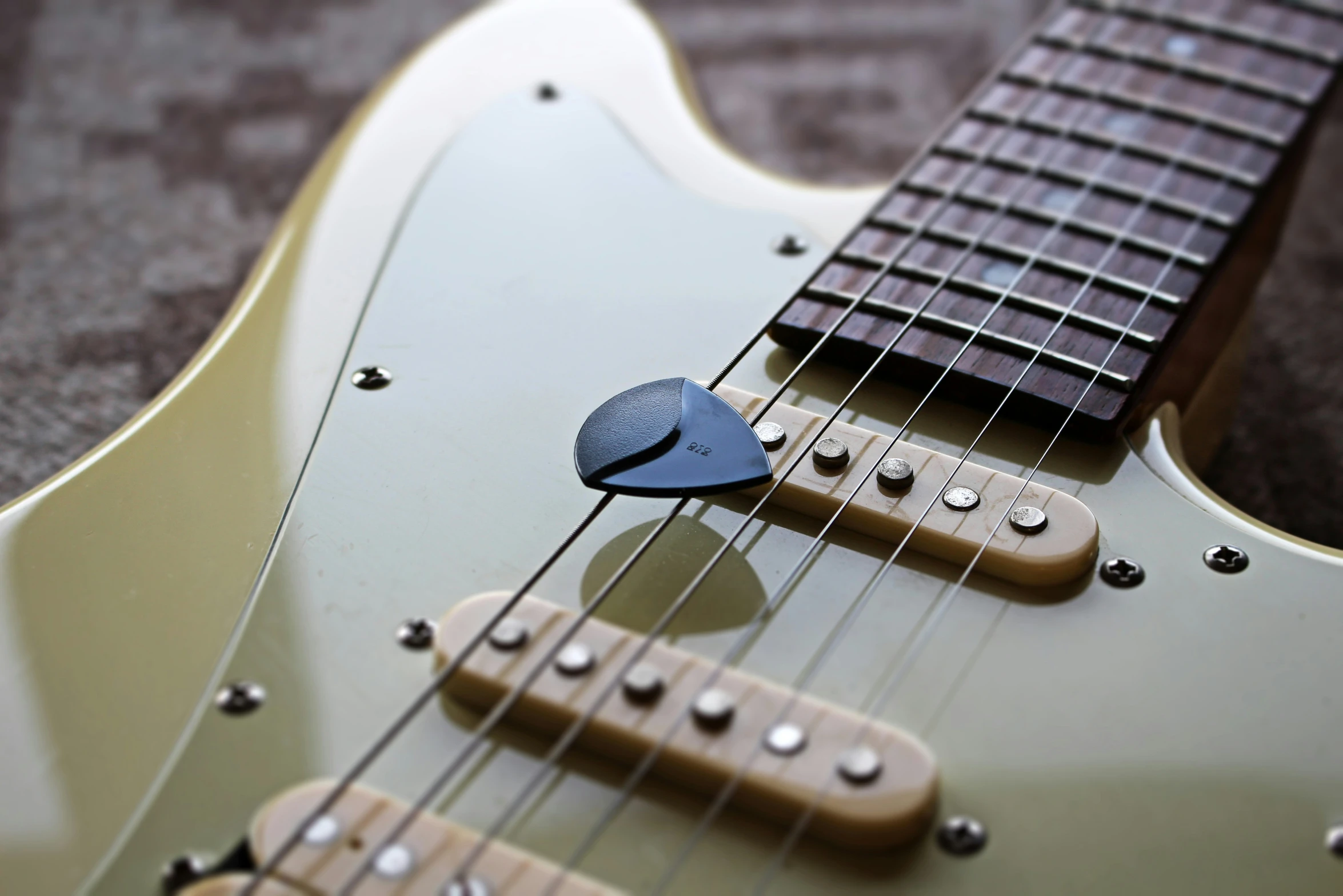 a close - up of a fretset guitar picker on a green guitar