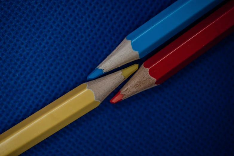 two different colored pencils on a blue table