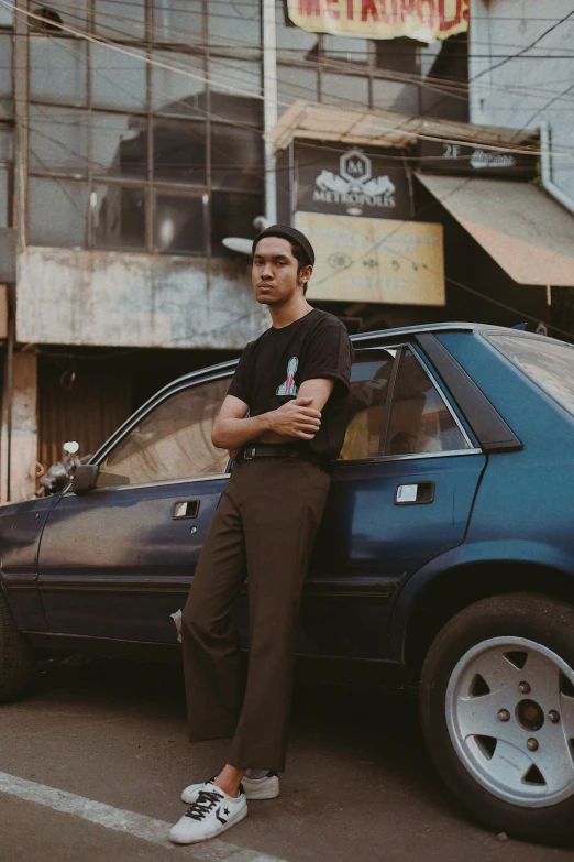 a man standing next to a blue car on the street