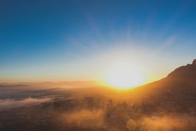 a bright sun is setting over a foggy city