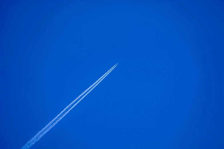 the plane is flying high in the blue sky