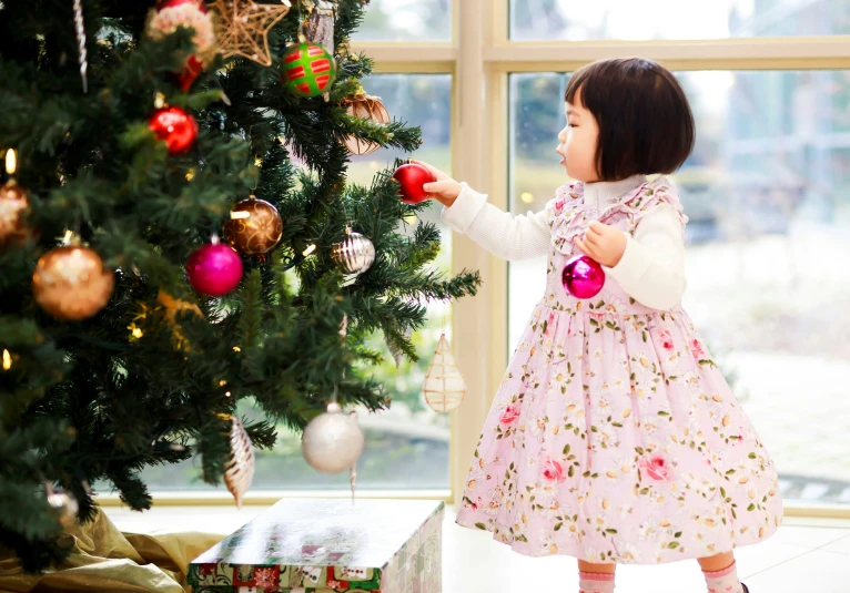 little girl looking at ornament on the tree
