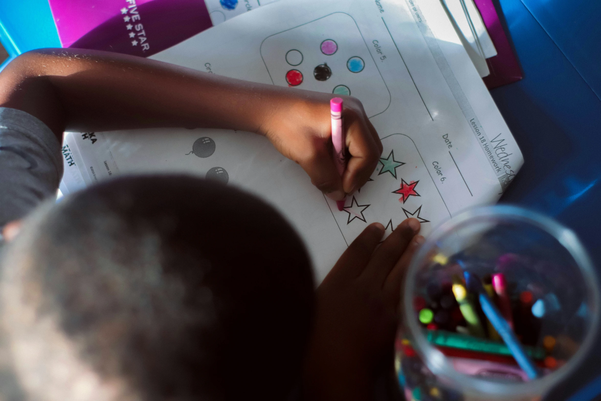 an image of child doing coloring with crayons