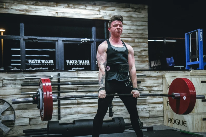 a man standing at the top of a barbell in the gym