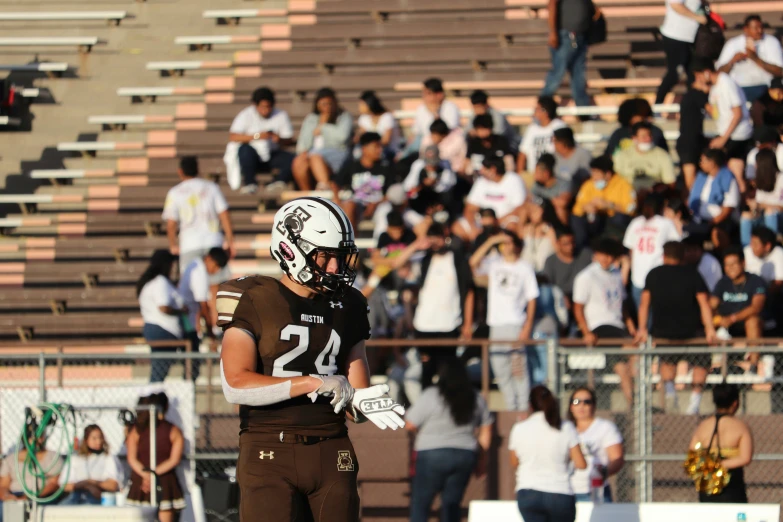 a football player holding onto his helmet while standing in the field