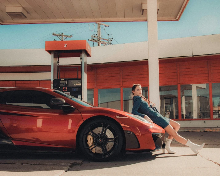 a person sits on the hood of a car