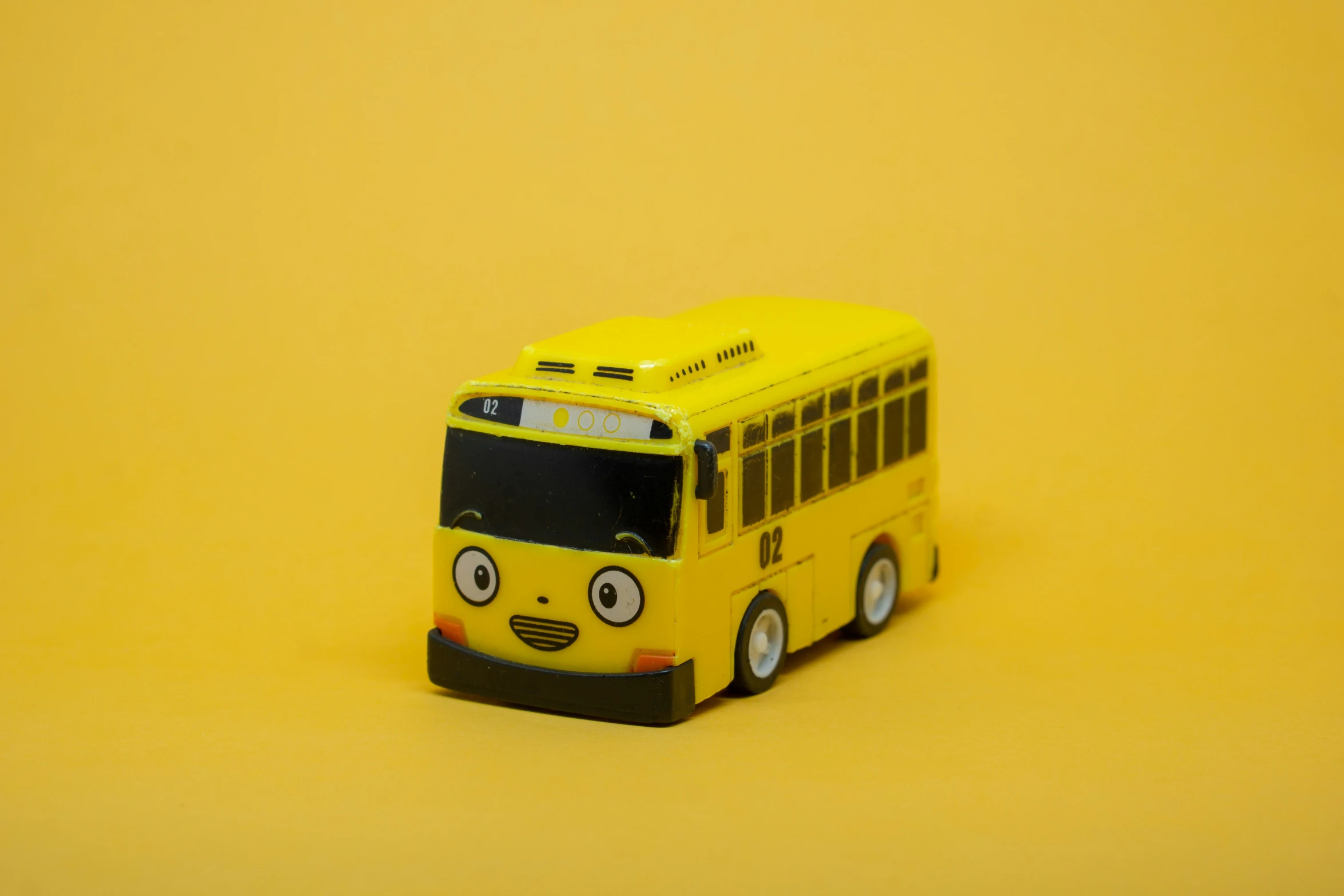 a toy bus is sitting on a yellow background