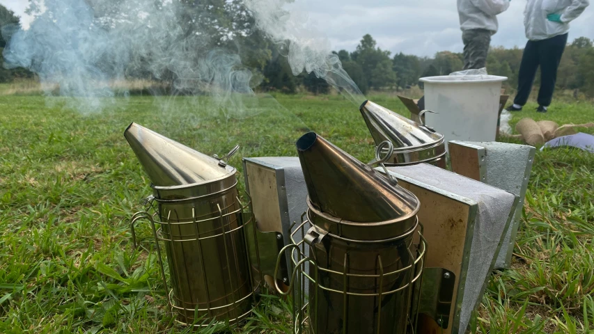 a field filled with metal trash cans covered in smoke