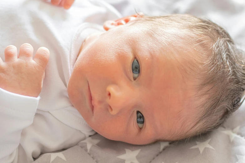 a baby in a white shirt laying down on a bed