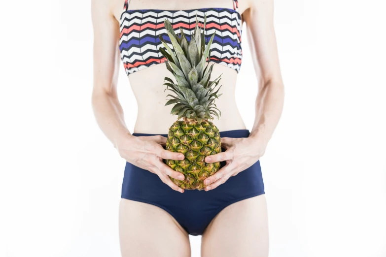 a woman wearing blue bikinis and holding a pineapple
