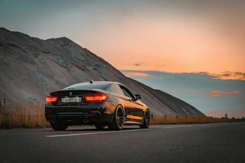 a car driving down a road past a mountain