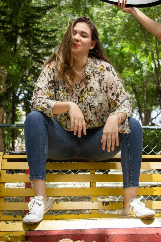 the woman is sitting on a bench looking up at a frisbee