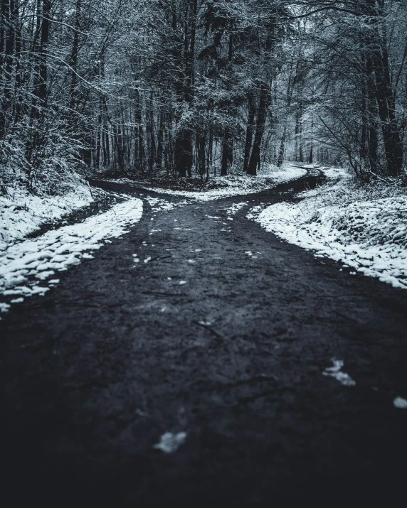 a dark road with lots of snow on top of it