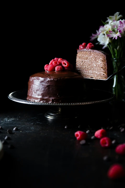 two chocolate cakes are on plates next to flowers