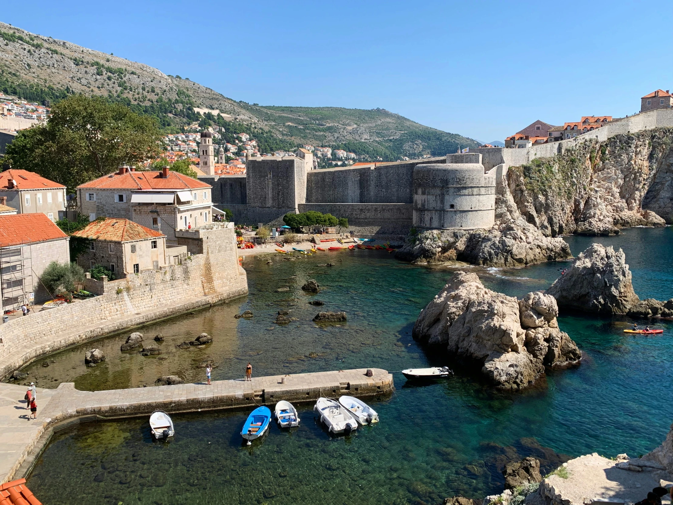 several boats in the water near an old stone wall and city buildings