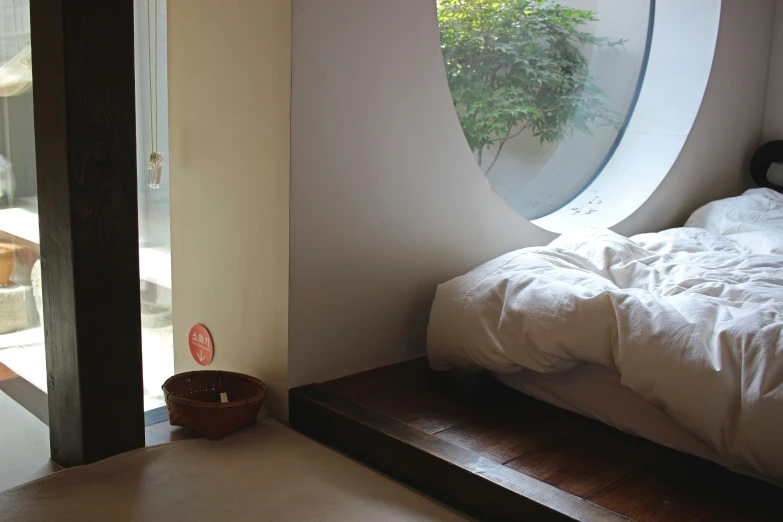 white sheets sit on top of a bed with a round window