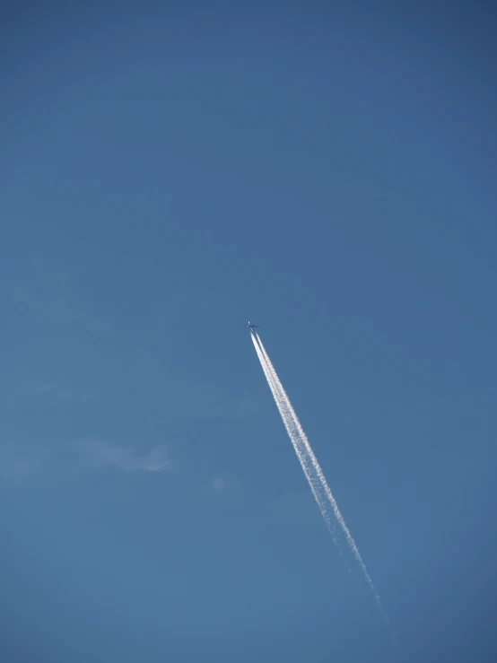 a jet flying in the air with its contrails behind