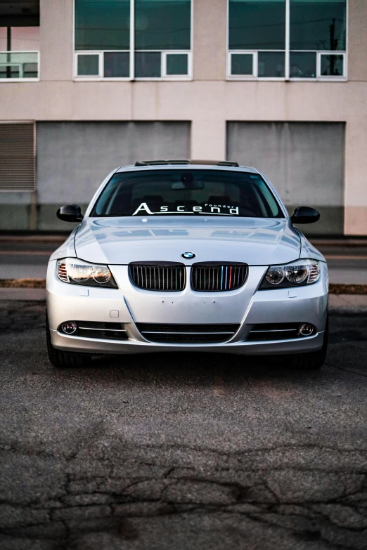 a silver bmw on the street in front of a building