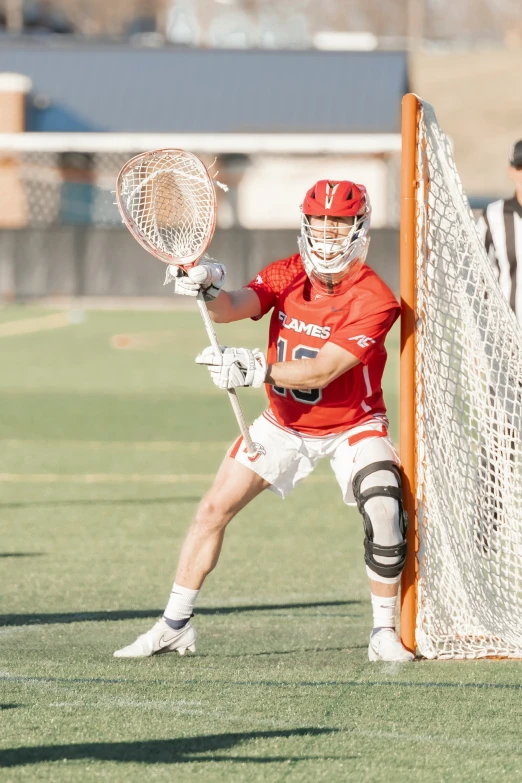 a lacrosse goalie holds his arm out to block the ball
