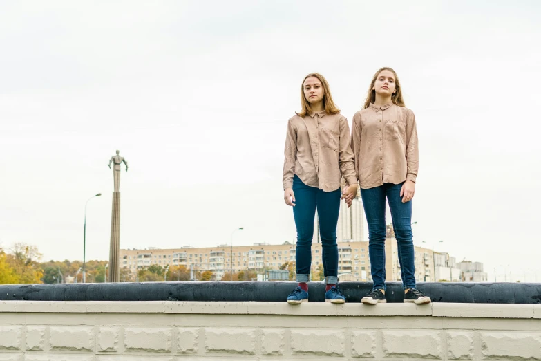 two girls standing on the ledge of a city park