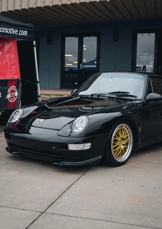 black car with gold rims parked in front of a commercial van