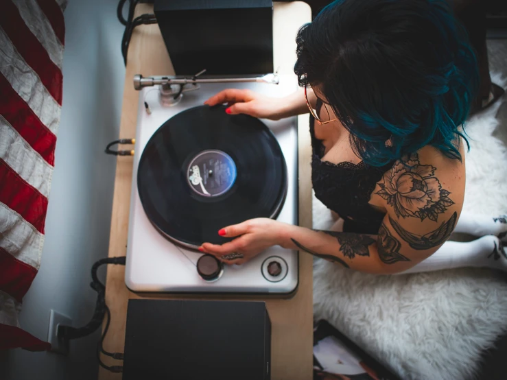 the woman in tattoos holds onto an old record