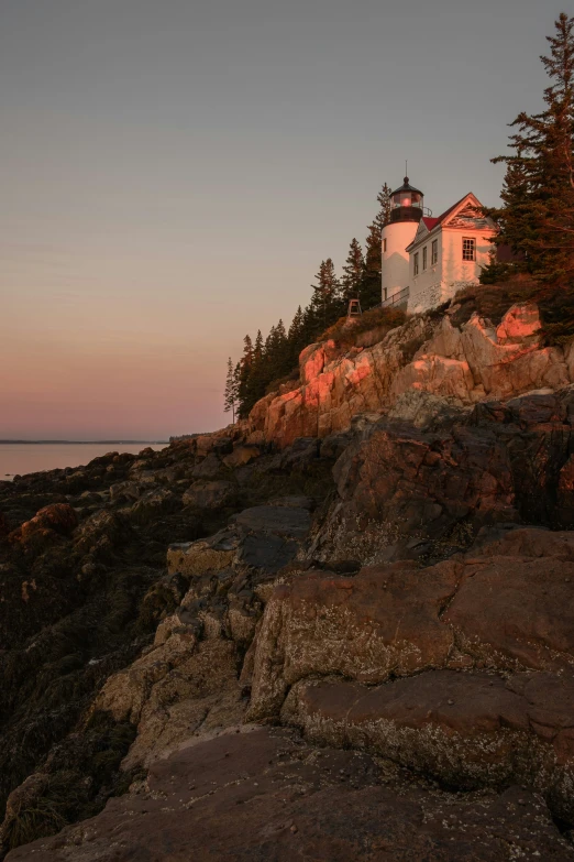 a lighthouse sits on top of some rocks by the ocean