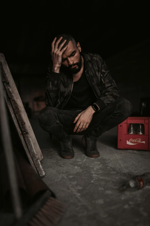 the man is sitting down near a building in the dark