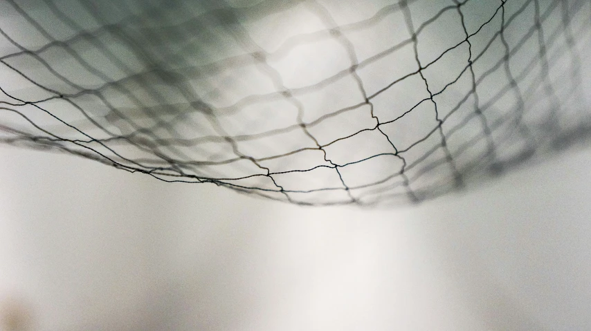 the shadows of a basketball net on a white wall