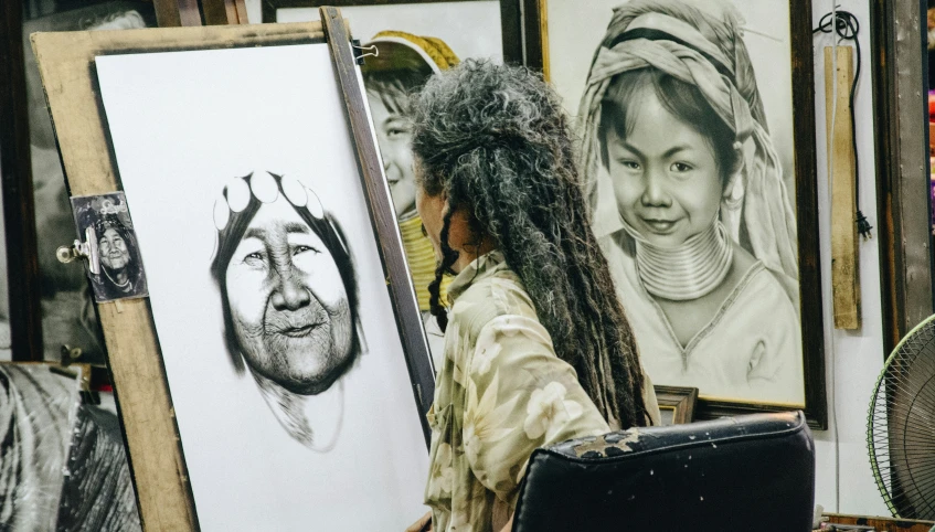 a woman holding an open bag walking past some drawings