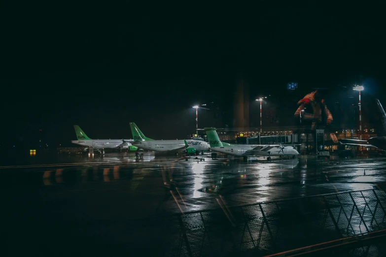 two planes are parked in the dark on a rainy night