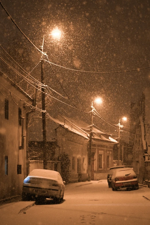 cars parked on a snowy street at night