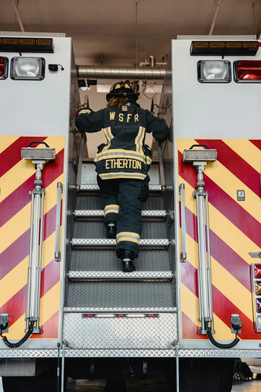 a fireman is climbing up the stairs of his fire truck