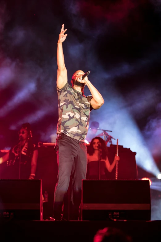 a man in camouflage shirt and hat singing on stage