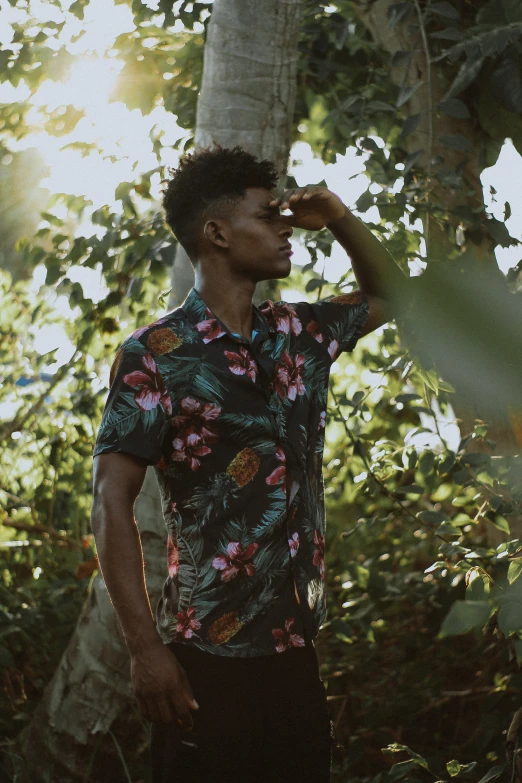 a man in hawaiian shirt posing near some trees