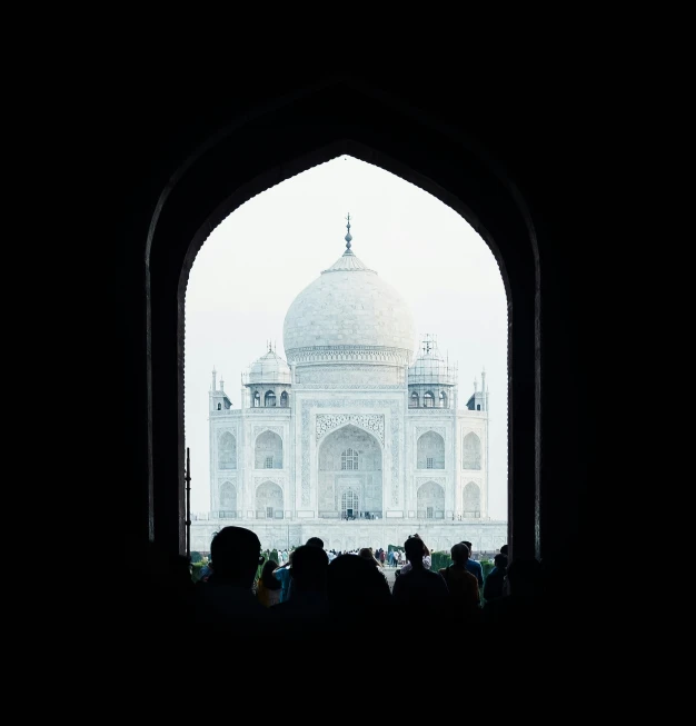 several people are looking through an arch at a white building