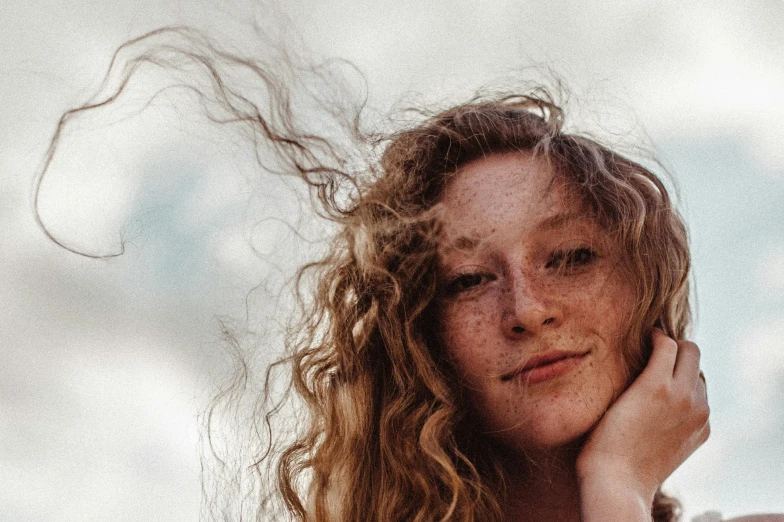 a woman with long, curly hair is looking over her shoulder