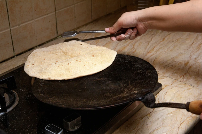 a person cooking on a small stove with food in it