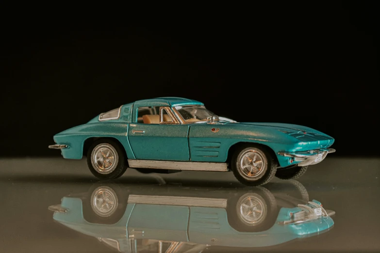 an old fashioned blue model car on a reflective surface