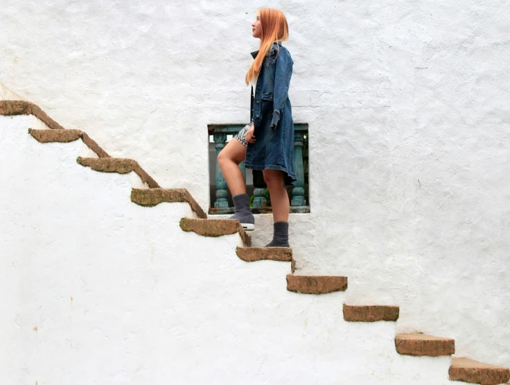 a woman with orange hair walking up a stairway