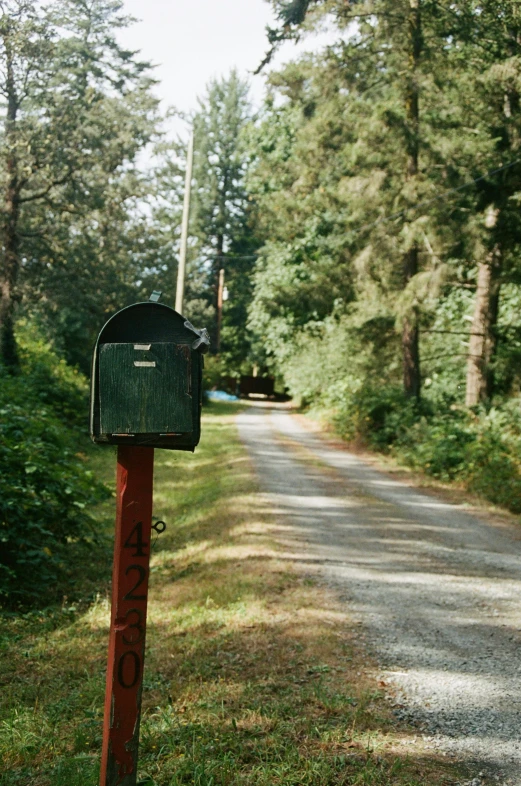 a mailbox on a red post by a road